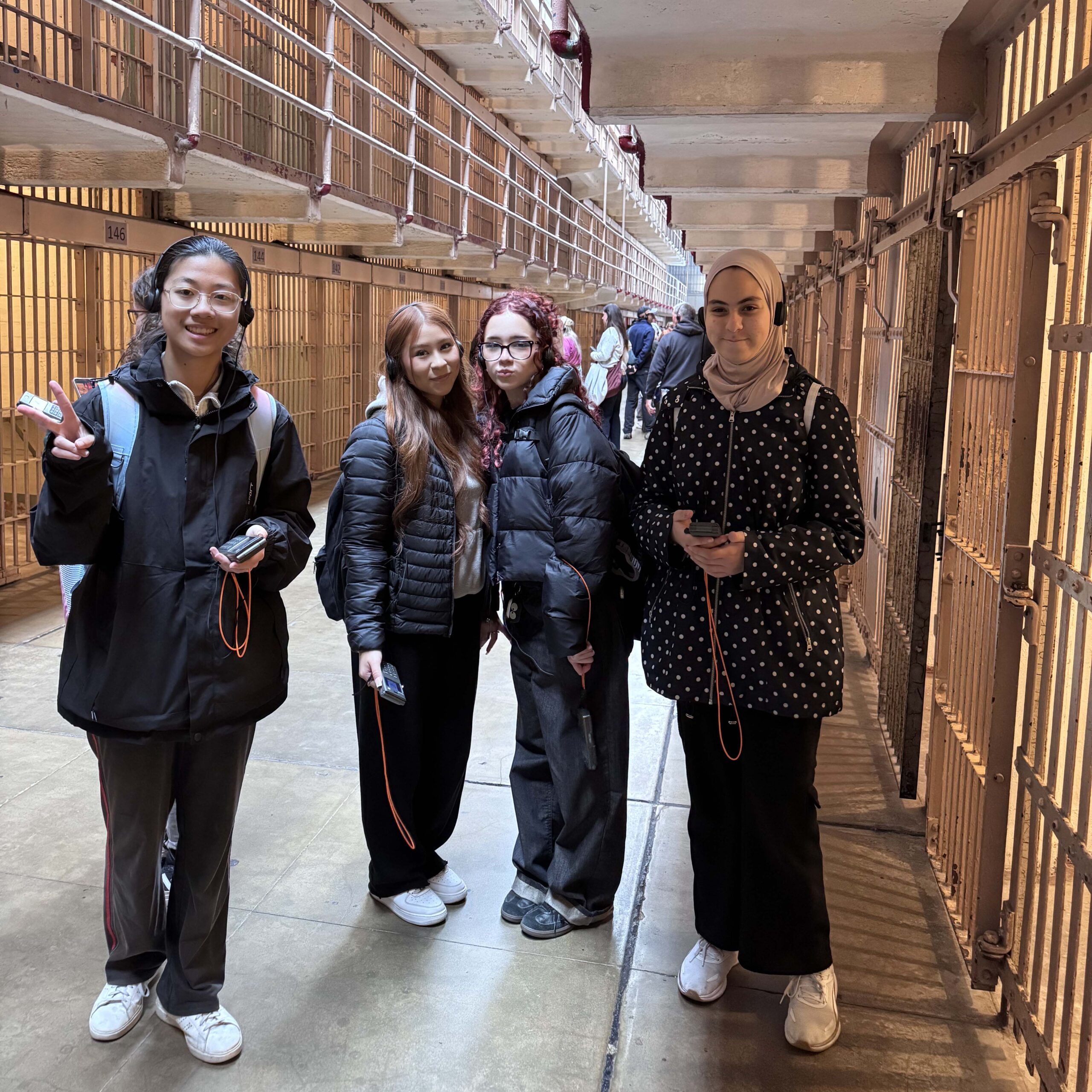 Four students wearing audio headsets while standing inside Alcatraz Prison.