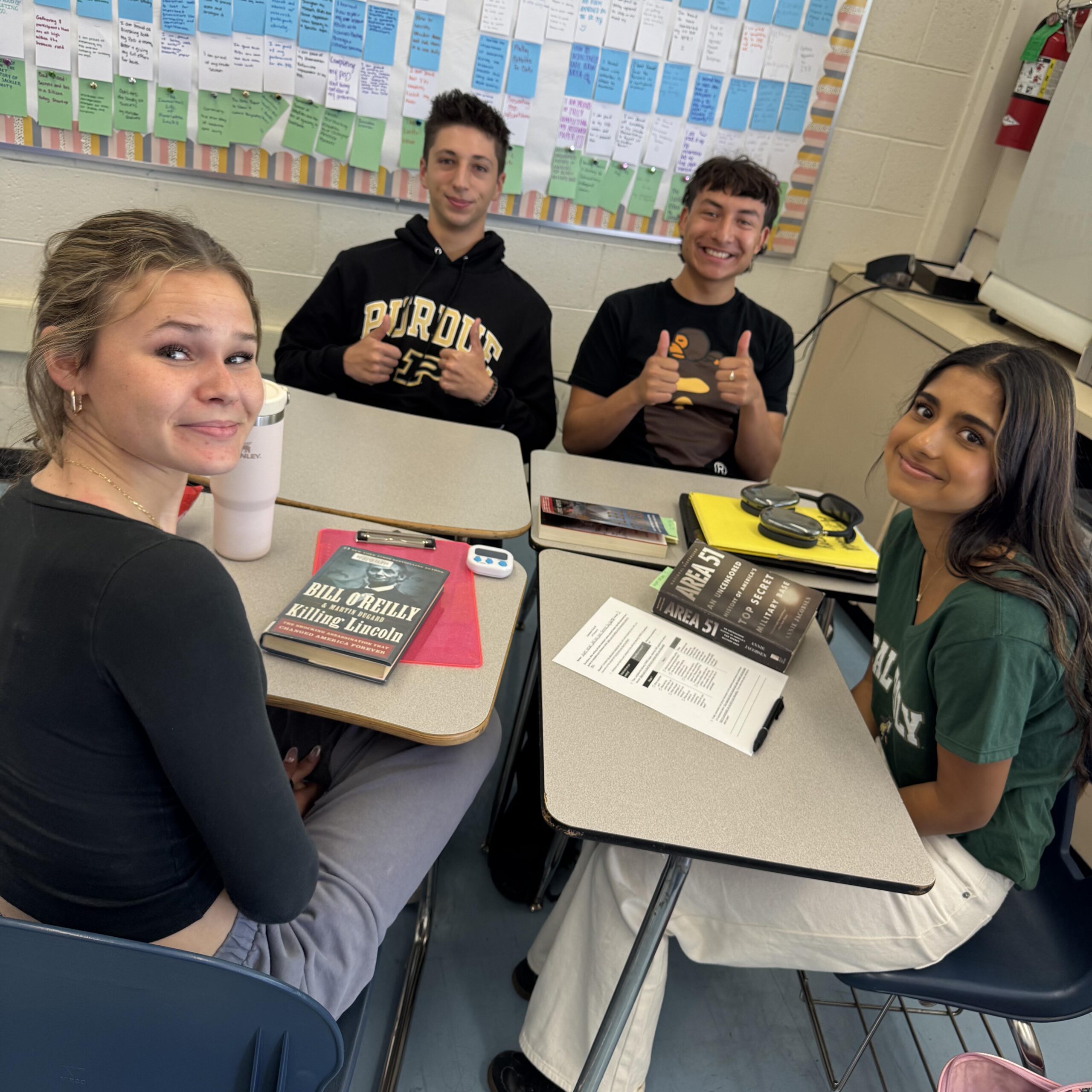 Four students working together with books and papers on table